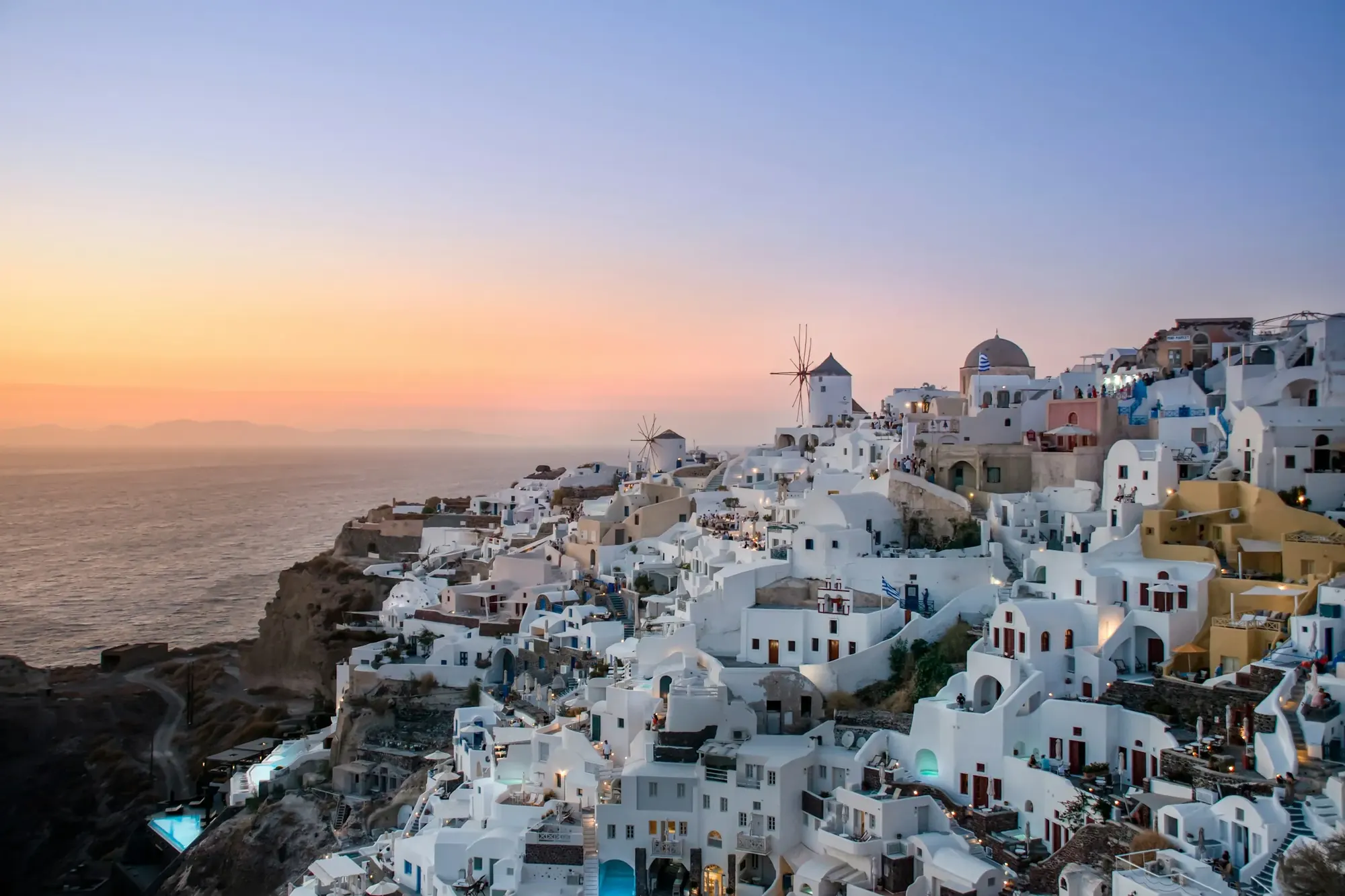 A whitewashed village on the cliff at sunset, with a windmill