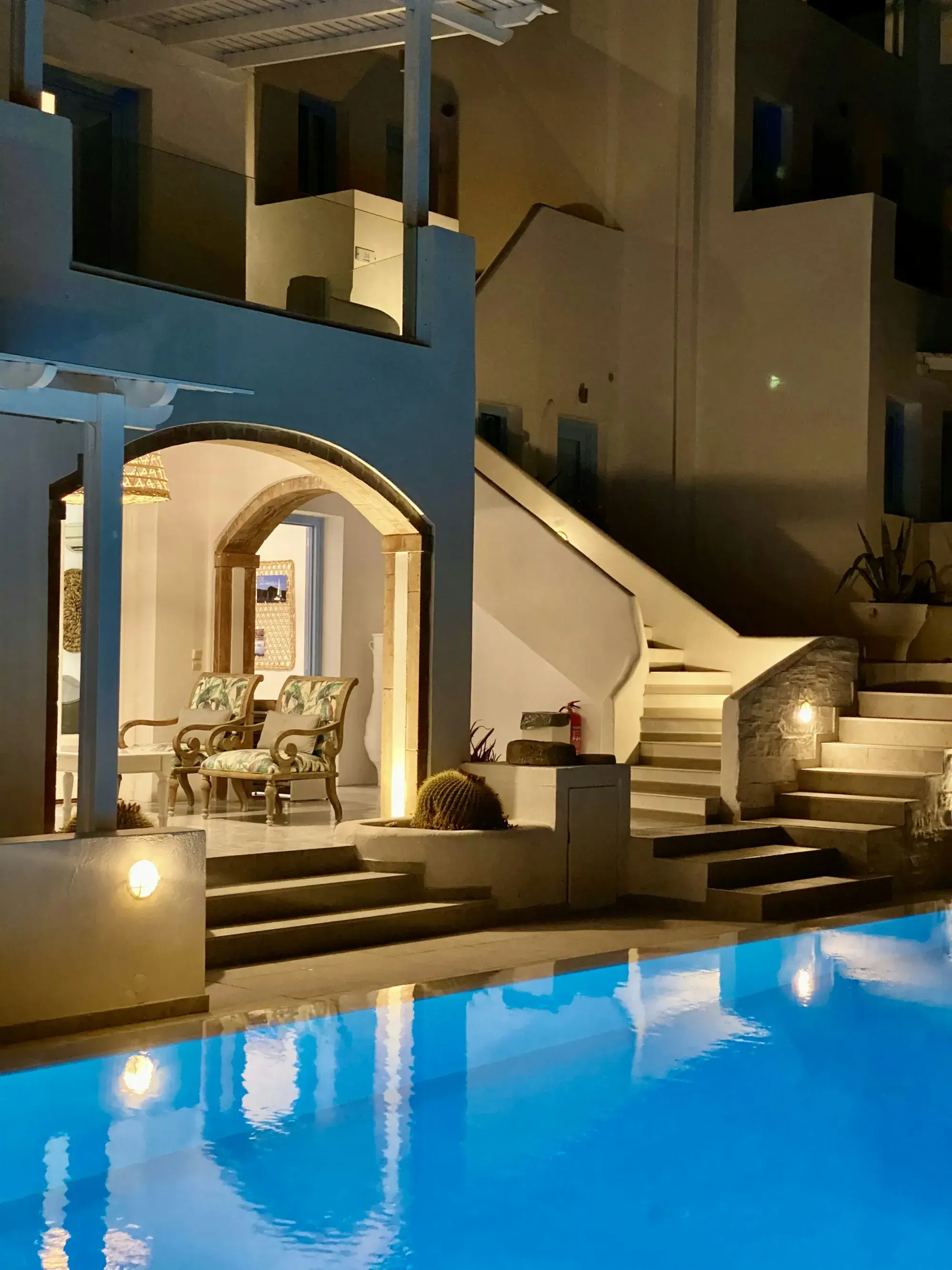 A small hotel courtyard at dusk, lit around a blue pool